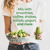 Person holding a bowl of salad and a bottle of green juice with text about using it with smoothies and other foods.